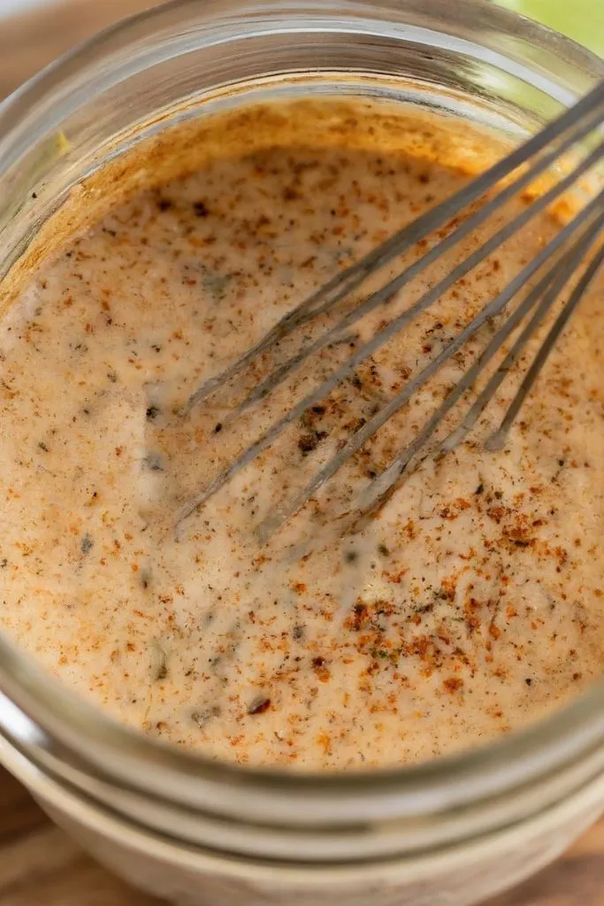 A mixture of lime juice, taco seasoning, and sour cream in a mason jar.